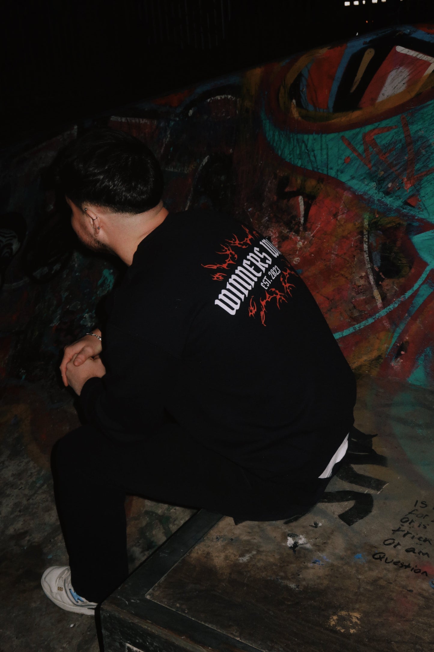 A professional skateboard rider wearing the Winners Win graphic sweatshirt at a skatepark in Belfast