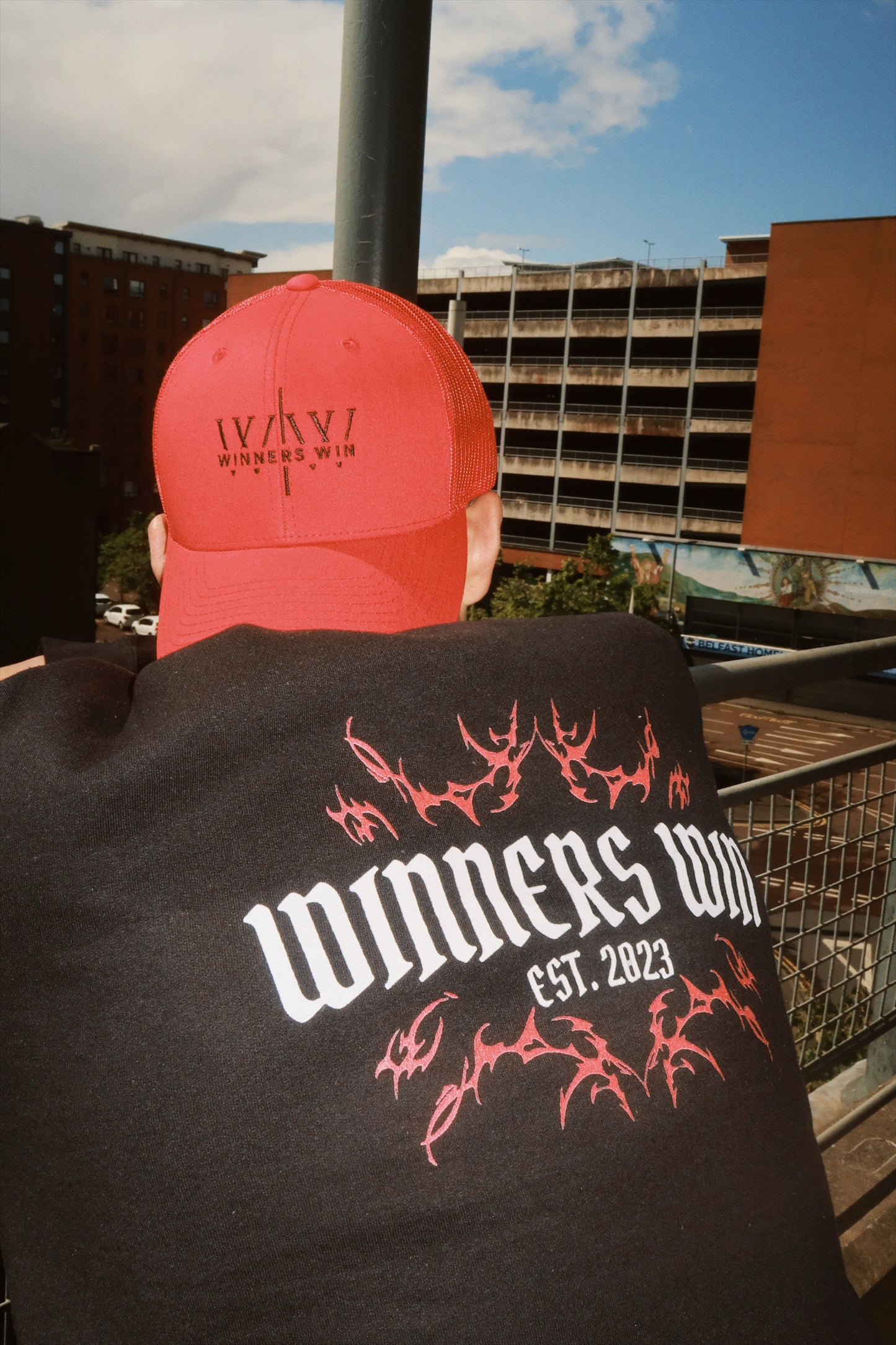 The red Winners Win cap being worn by a model over looking Belfast city centre