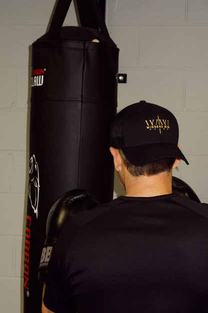 Boxer wearing the winners win black hat while punching the bag