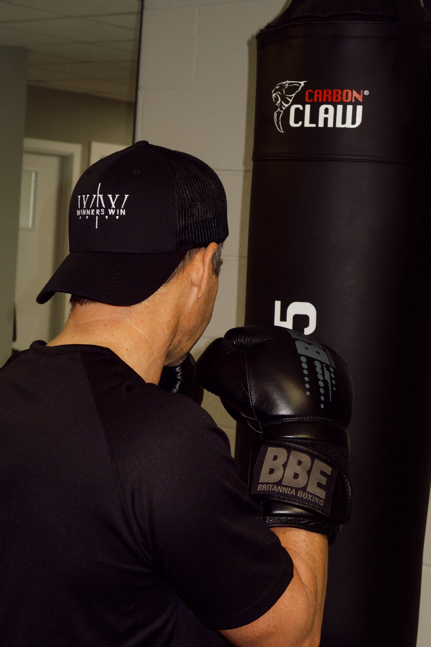 boxer wearing the winners win black and white cap while punching the bag 